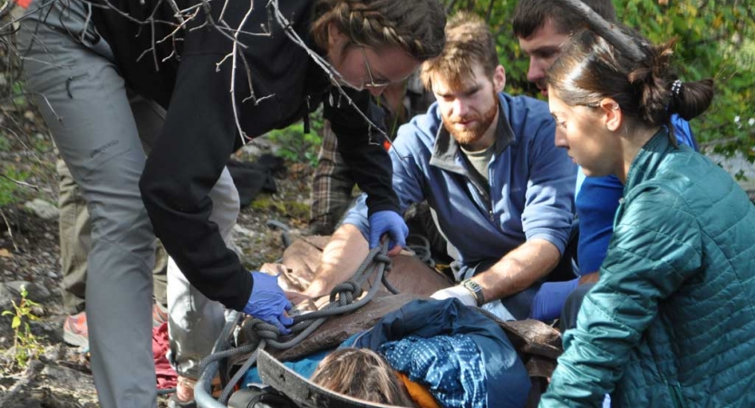 four people participate in a wilderness first responder exercise